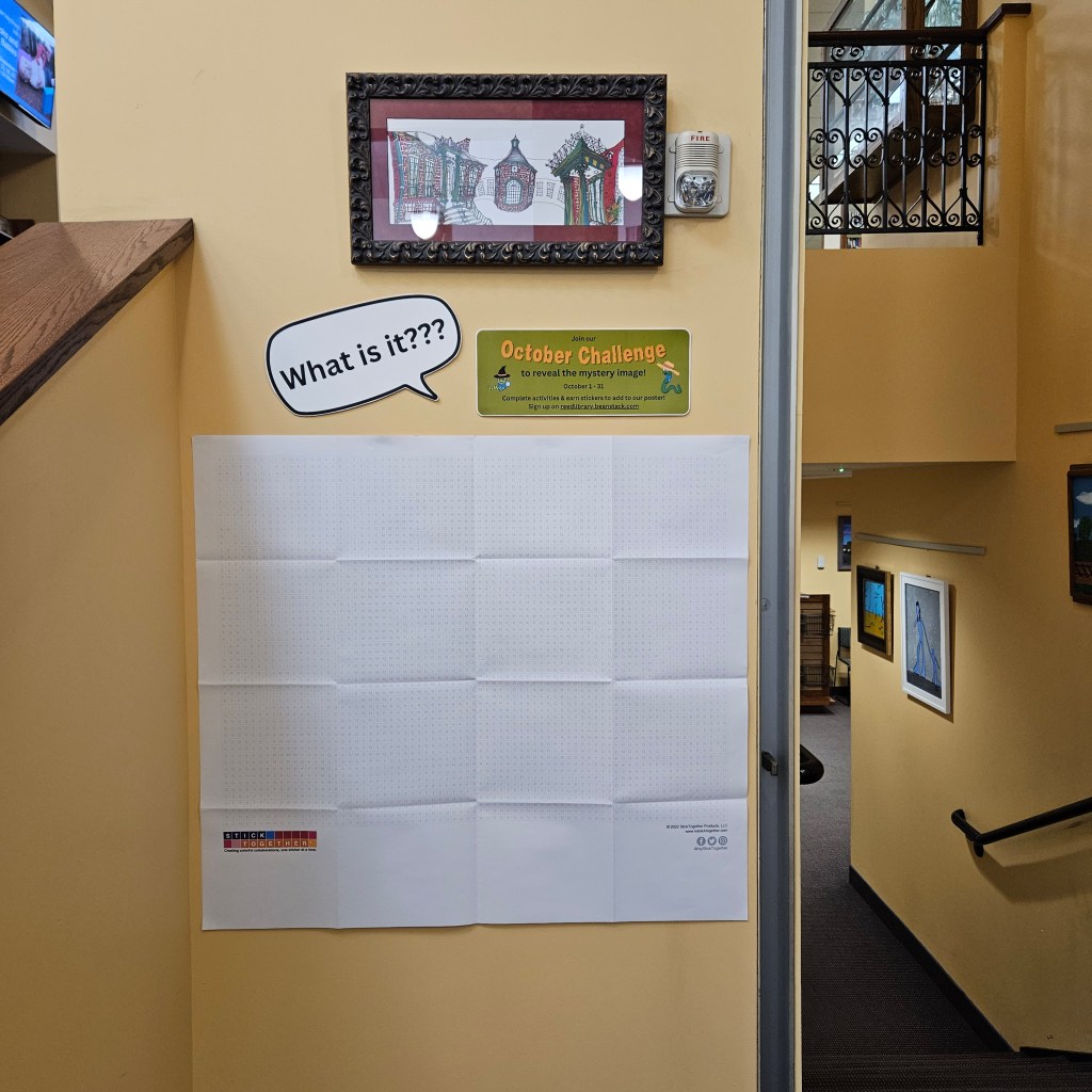 What is it? A blank poster hanging on the wall with a sign about the October Challenge above.