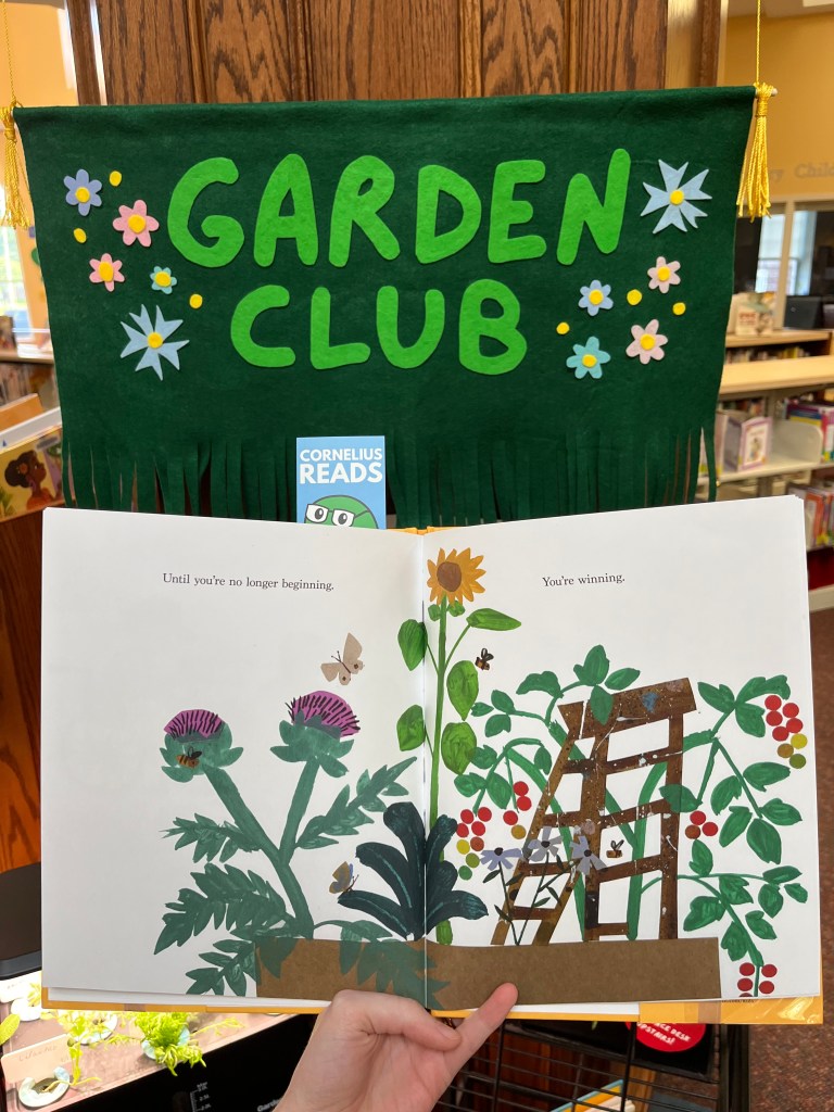 Photograph of a page in Something, Someday that reads "Until you're no longer beginning. You're winning." The book is held in front of a felt banner that reads "Garden Club"