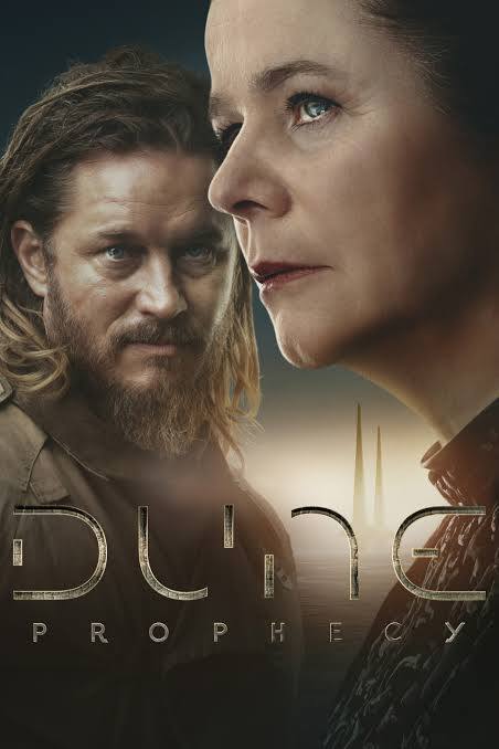 Futuristic close up of a woman in high necked dress looking into the distance. Behind her, a man with beard and long hair looks at her.