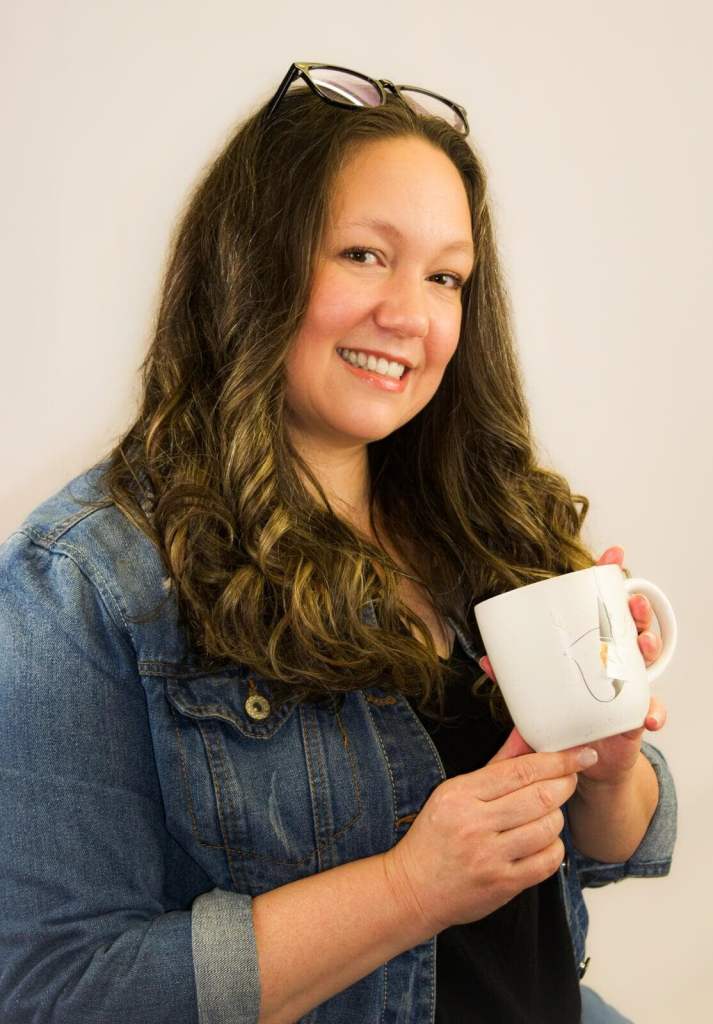 Julie Hatcher, a woman with long dark hair, smiling and holding a coffee cup