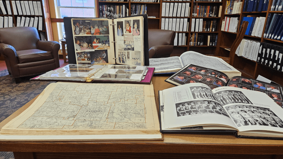 a table filled with old maps, yearbooks, and personal albums.
