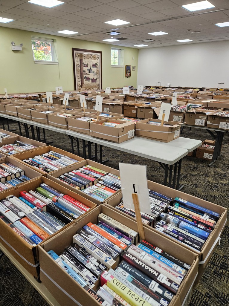 many boxes of books on tables, filling a room