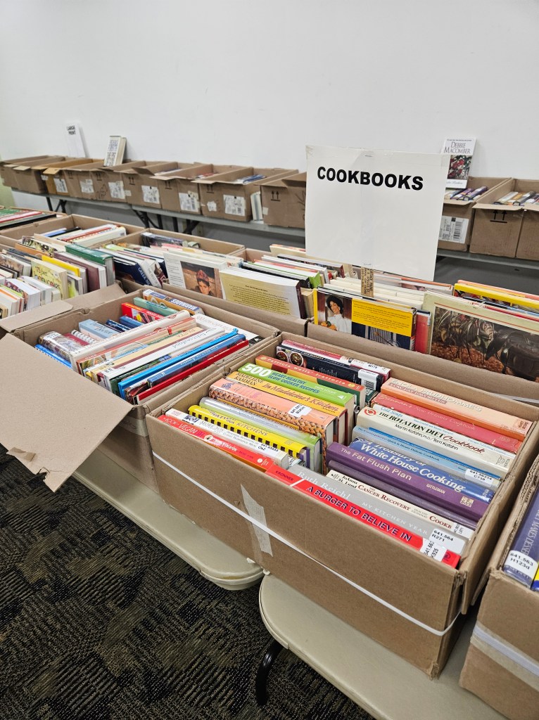 many boxes of books on tables, filling a room