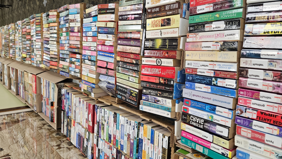 sideways view of a very long table filled with books set on their ends so that the spines are visible.