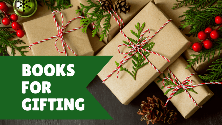 book shaped gifts wrapped in brown paper lying among pine boughs and holiday decorations