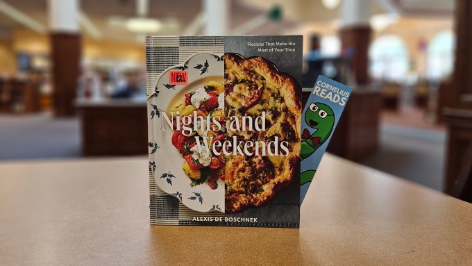 a book titled "Nights and Weekends" sits upright on a table, with a Cornelius Reads bookmark peeking out the side pages